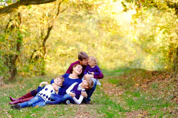 Porträtt av unga föräldrar med tre barn. Mor, far, två barn bröder pojkar och liten söt småbarn syster flicka har roligt tillsammans i höstskogen. Lycklig familj på fem — Stockfoto