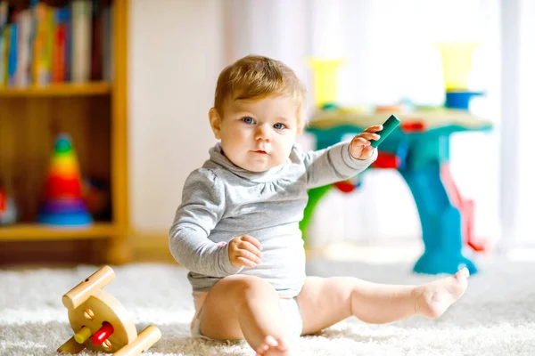 教育用のおもちゃで遊んでいる愛らしい赤ちゃんの女の子。家でカラフルな異なる木製のおもちゃで楽しんでいる幸せな健康的な子供。自然のおもちゃを持つ子供たちのための初期の開発. — ストック写真