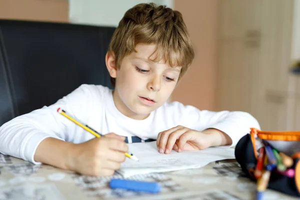 Müder kleiner Junge zu Hause, der morgens vor Schulbeginn Hausaufgaben macht. Kleines Kind beim Sport, drinnen. Grundschule und Bildung. — Stockfoto