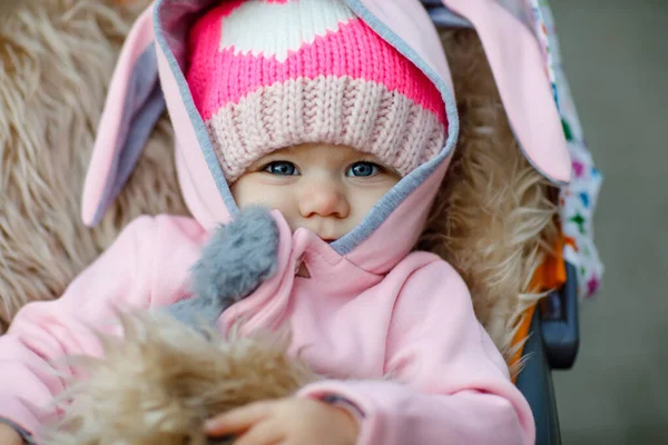 Cute little beautiful baby girl sitting in the pram or stroller on autumn day. Happy smiling child in warm clothes, fashion stylish baby coat. Healthy toddler going for walk on fresh air with parents — Stock Photo, Image