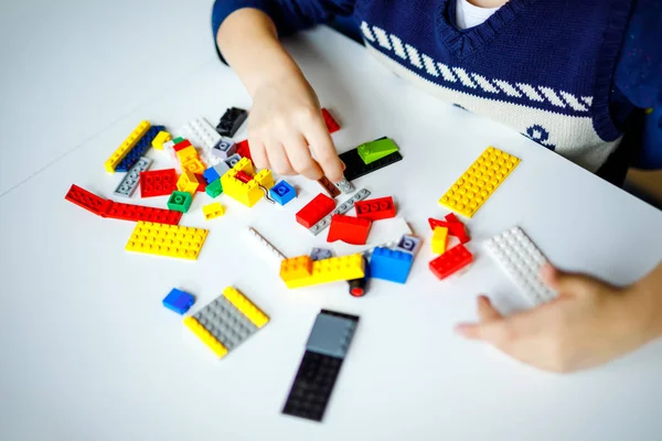 Close-up de mãos de criança brincando com lotes de blocos de plástico coloridos. Criança se divertindo com a construção e criação de robô. Lazer criativo moderno técnico e robótico . — Fotografia de Stock