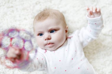 Beyaz arka planda renkli top oyuncağıyla oynayan sevimli, tapılası bir bebek. Yeni doğan çocuk, kameraya bakan küçük kız. Aile, yeni hayat, çocukluk, başlangıç konsepti. Bebek öğrenme çıngırağı.