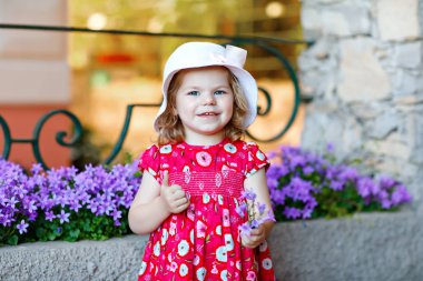 Pembe elbiseli, moda elbiseli, diz altı çoraplı ve şapkalı güzel küçük bir kız çocuğunun portresi. Renkli evin önünde poz veren mutlu sağlıklı bebek..