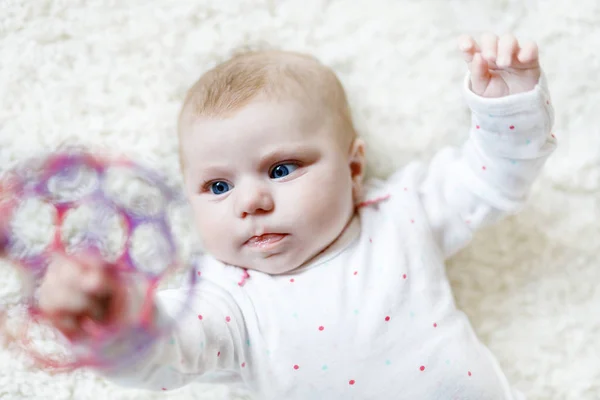Bonito bebê recém-nascido adorável brincando com brinquedo colorido bola no fundo branco. Criança recém-nascida, menina olhando para a câmera. Família, nova vida, infância, conceito inicial. Aprendizado bebê agarrar chocalho. — Fotografia de Stock