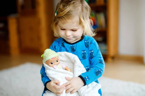 Schattig schattig klein peutermeisje dat met een pop speelt. Gelukkig gezond baby kind hebben plezier met rollenspel, spelen moeder thuis of kinderkamer. Actieve dochter met speelgoed. — Stockfoto