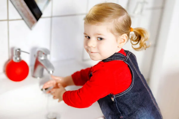 Schattig klein peuter meisje wassen handen met zeep en water in de badkamer. Schattig kind leren schoonmaken lichaamsdelen. Ochtendhygiëne. Gelukkig gezond kind thuis of in de kinderkamer. — Stockfoto