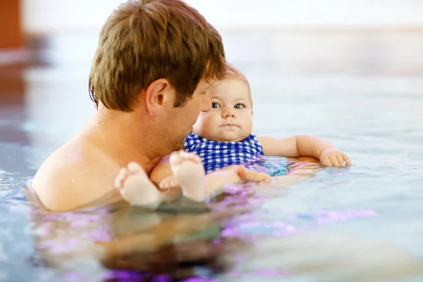 Happy middle-aged father swimming with cute adorable baby daughter in whirl pool. Smiling dad and little child, girl of 6 months having fun together. Active family spending leisure in spa hotel