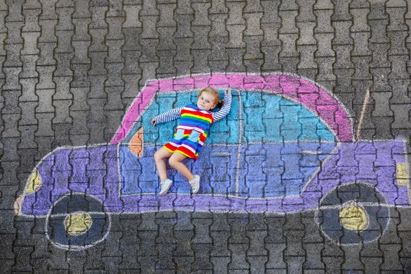 Entzückendes kleines Mädchen, das mit bunten Kreiden spielt und ein großes Auto-Bild auf Asphalt malt. glückliches Baby, das draußen spielt. Kreative Freizeit für Kinder im Sommer — Stockfoto
