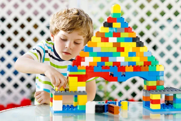 Μικρό ξανθό παιδί και το παιδί αγόρι παίζει με πολλά πολύχρωμα πλαστικά μπλοκ. — Φωτογραφία Αρχείου