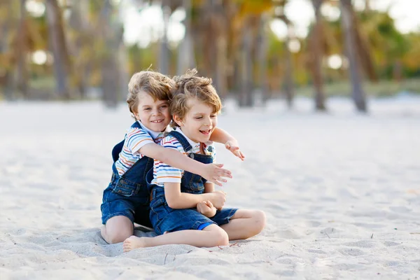 Dwa małe dzieci Chłopcy świetnie się bawią na tropikalnej plaży, szczęśliwy przyjaciele gra, pojęcie przyjaźni. Rodzeństwo braci, bliźniaki w rodzinie wyglądają dłońmi na tle. Rodzinne wakacje na Malediwy. — Zdjęcie stockowe