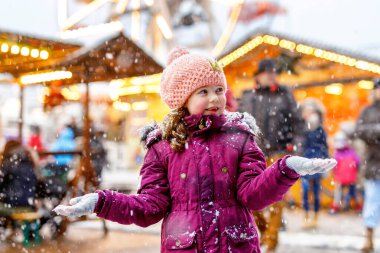 Küçük sevimli kız eğleniyor geleneksel Alman Noeli piyasaya güçlü kar yağışı sırasında... Almanya, Frankfurt geleneksel aile Pazar keyfi mutlu bir çocuk. Renkli giysileri gülen kızı