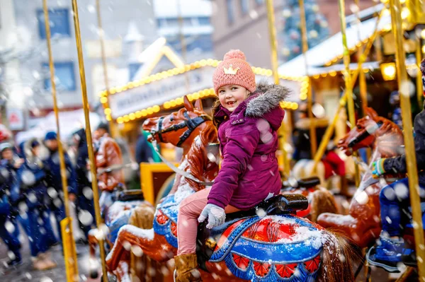 Adorable little kid girl riding on a merry go round carousel horse at Christmas funfair or market, outdoors. Happy child having fun on traditional family xmas market in Dresden, Germany — Stock Photo, Image