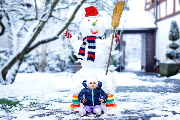 Kış günü kar ve kardan adamla küçük tatlı bir kız bebek. — Stok fotoğraf