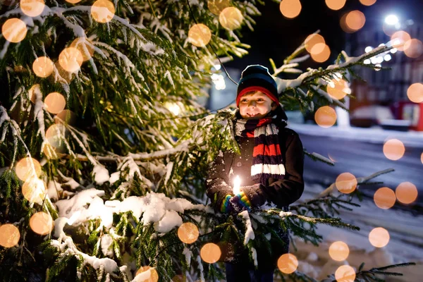 Niño divertido en ropa colorida jugando al aire libre durante las nevadas. Ocio activo con niños en invierno en días fríos nevados. Feliz niño sano en el mercado de Navidad en Alemania — Foto de Stock