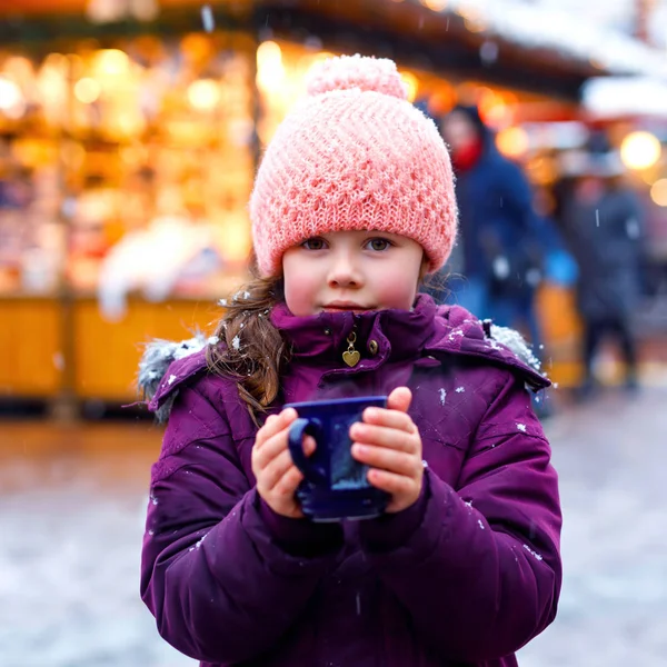 Pequena menina bonito miúdo com xícara de chocolate quente fumegante ou crianças soco. Criança feliz no mercado de Natal na Alemanha. Lazer tradicional para famílias em xmas . — Fotografia de Stock