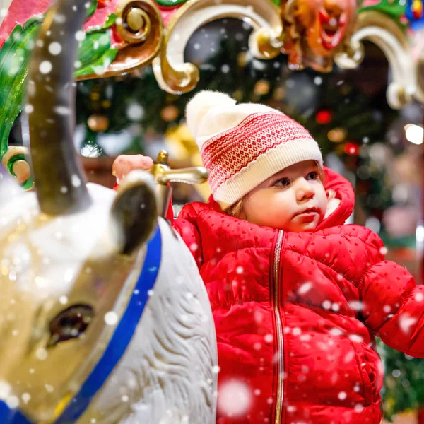 Rozkošné malé dítě dívka na koni na veselé obejít Kolotočových koně na Vánoce lunapark nebo trh, venku. Šťastný chlapec dítě baví na tradiční rodinný vánoční trh v Německu — Stock fotografie