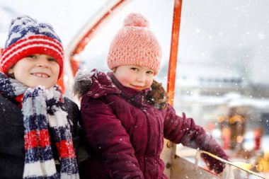 İki küçük çocuk, erkek ve kız şiddetli kar yağışı sırasında geleneksel Alman Noel pazarında dönme dolapta eğleniyorlar. Mutlu çocuklar Almanya 'da aile pazarının tadını çıkarıyorlar. Sevgili kardeşlerim..