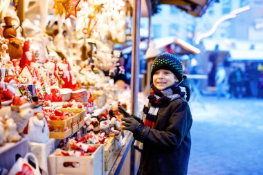 Noel pazarında dekorasyon seçen sevimli çocuk. Oyuncaklar için alışveriş yapan güzel bir çocuk ve ağaç için dekoratif süsler. Almanya 'da Xmas pazarı.