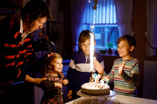 Adorável menina criança comemorando o terceiro aniversário. Criança, dois meninos crianças irmãos e pai, juntamente com bolo e velas. Retrato familiar saudável feliz com três crianças — Fotografia de Stock