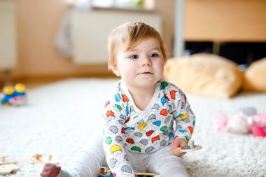 Evde ya da çocuk odasında ahşap yapboz gibi eğitici oyuncaklarla oynayan güzel bir kız bebek. Mutlu sağlıklı çocuk renkli oyuncaklarla eğleniyor. Çocuk farklı yetenekler öğreniyor