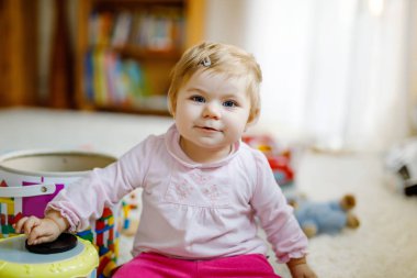 Evde ya da çocuk odasında eğitici oyuncaklarla oynayan güzel, güzel bir kız bebek. Mutlu sağlıklı çocuk renkli oyuncaklarla eğleniyor. Çocuk farklı yetenekler öğreniyor.