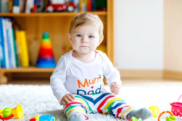 Adorável menina brincando com brinquedos educativos no berçário. Criança saudável feliz se divertindo com brinquedos diferentes coloridos em casa. Desenvolvimento do bebê e primeiros passos, aprendendo a jogar e agarrar. — Fotografia de Stock