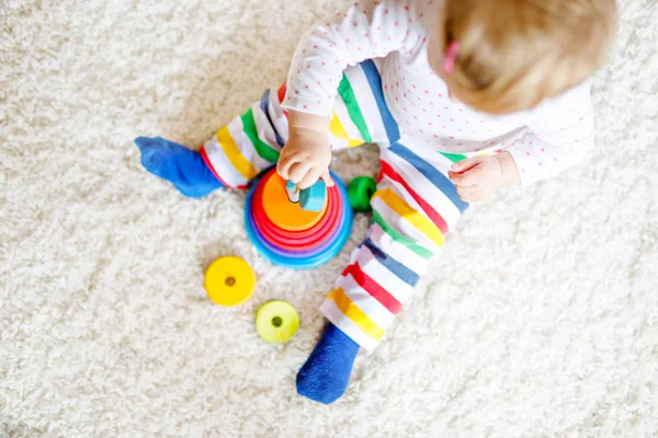 Entzückend süße schöne kleine Mädchen spielen mit Lernspielzeug zu Hause oder im Kinderzimmer. Glückliches gesundes Kind, das Spaß an der bunten hölzernen Regenboy-Spielzeugpyramide hat. Kind lernt andere Fähigkeiten — Stockfoto