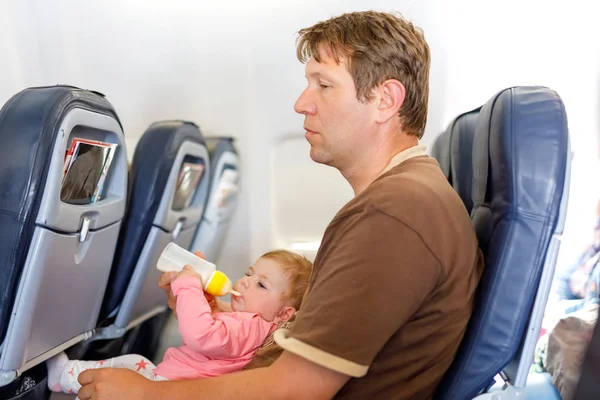 Батько тримає свою доньку під час польоту на літаку, що йде у відпустку — стокове фото