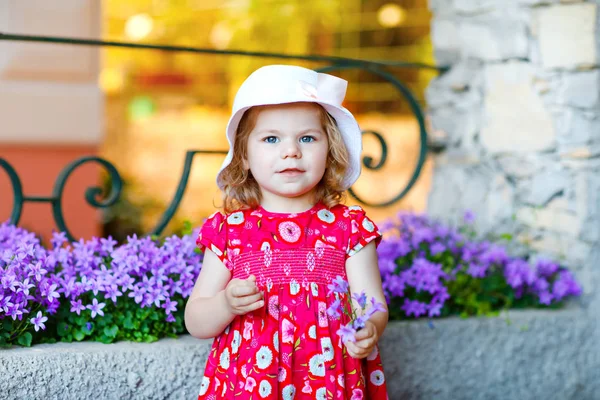Портрет красивої маленької горегі милої дівчинки-малятка в рожевому літньому одязі, модному платті, шкарпетках для колін і капелюсі. Щаслива здорова дитина позує перед барвистим будинком . — стокове фото
