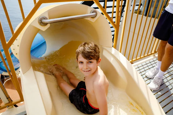 Piccolo ragazzo felice che scivola sul tubo dell'acquascivolo nel parco del resort. Bambino sano divertirsi . — Foto Stock