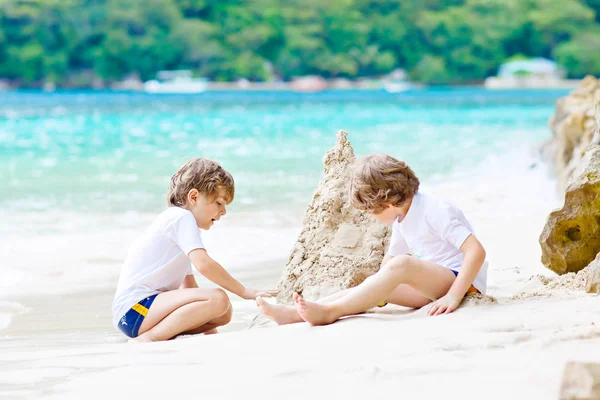 Два мало діти веселяться із пісок замок на тропічні пляжі Сейшельських островів. дітей, що грають разом на свою відпустку.. — стокове фото