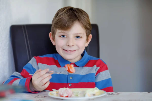 幸せな子供の男の子は、食事や軽食としてトマト、キュウリ、さまざまな野菜と新鮮なサラダを食べています。家庭や学校の食堂でおいしいと新鮮な食べ物を楽しむ健康な子供. — ストック写真