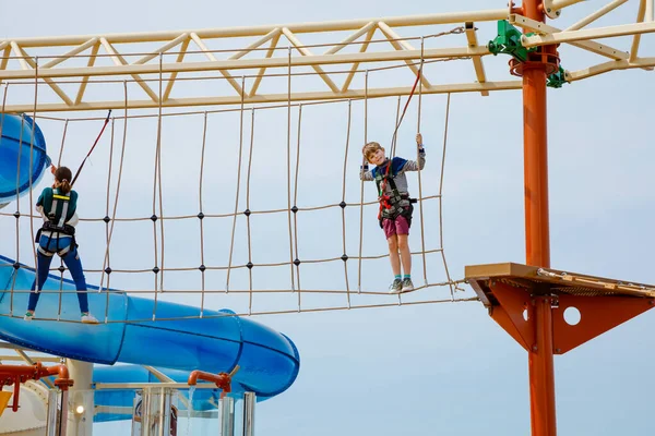 Joyeux petit garçon grimpant sur le sentier de la corde haute. Enfant actif faisant l'aventure et l'action sur les vacances en famille. Défi pour les enfants courageux . — Photo