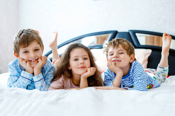 Three happy kids in pajamas celebrating pajama party. Preschool and school boys and girl having fun together