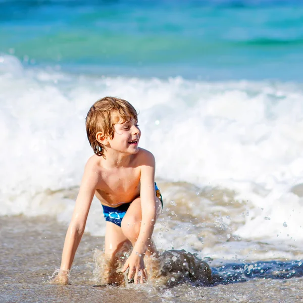 Adorable niño rubio divirtiéndose en la playa del océano. Emocionado niño jugando con olas, nadando, chapoteando y feliz por las vacaciones familiares en Miami, Florida, EE.UU. — Foto de Stock
