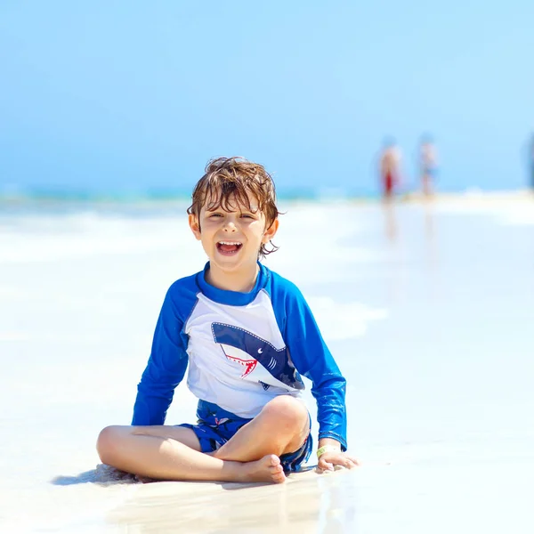 Adorable petit garçon blond s'amusant sur la plage tropicale de Jamaïque. Enfants excités jouant et surfant en maillot de bain protégé du soleil dans l'océan en vacances — Photo