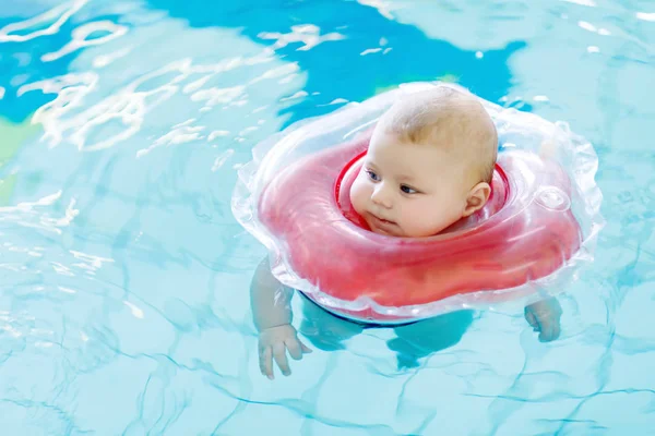 Piccolo bambino carino che impara a nuotare con anello di nuoto in una piscina coperta. neonato ragazza o ragazzo divertirsi in acqua. Tempo libero sano attivo e sport per neonati e bambini . — Foto Stock
