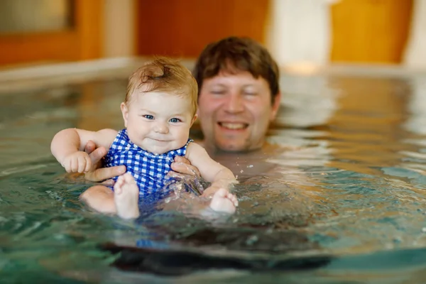 Feliz padre de mediana edad nadando con linda hija adorable en la piscina de hidromasaje. Papá sonriente y niño pequeño, niña de 6 meses divirtiéndose juntos. Vacaciones activas en familia en el hotel spa — Foto de Stock