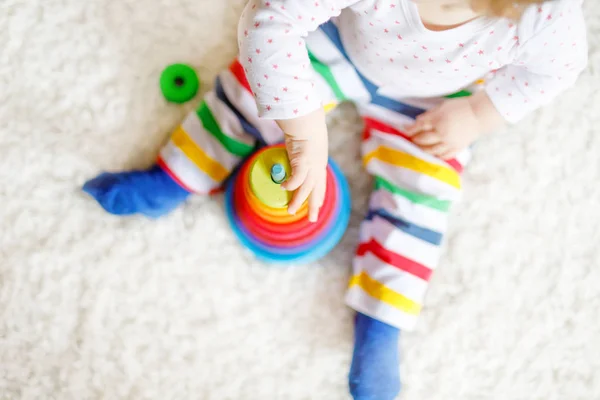 Adorable linda y hermosa niña jugando con juguetes educativos en casa o en la guardería. Feliz niño sano que se divierte con colorida pirámide de juguete Rainboy de madera. Niño aprendiendo diferentes habilidades —  Fotos de Stock