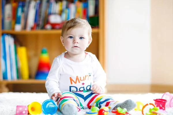 Adorável menina brincando com brinquedos educativos no berçário. Criança saudável feliz se divertindo com brinquedos diferentes coloridos em casa. Desenvolvimento do bebê e primeiros passos, aprendendo a jogar e agarrar. — Fotografia de Stock