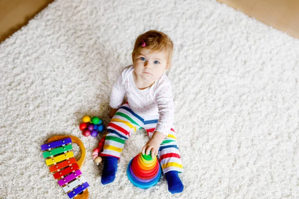 Adorable linda y hermosa niña jugando con juguetes educativos en casa o en la guardería. Feliz niño sano que se divierte con colorida pirámide de juguete Rainboy de madera. Niño aprendiendo diferentes habilidades —  Fotos de Stock