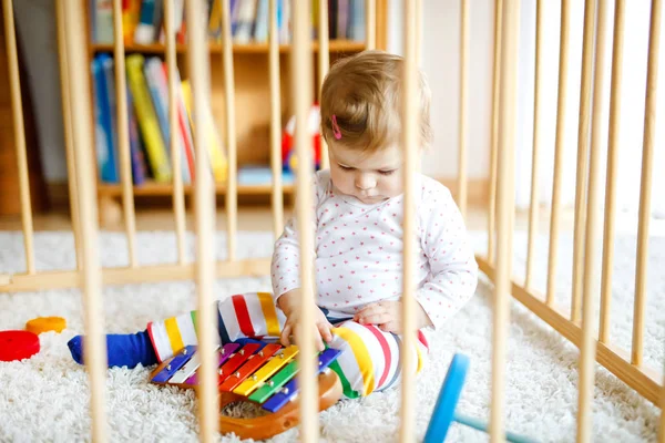 Mooi klein meisje dat in de box staat. Schattig schattig kind spelen met kleurrijk speelgoed. Thuis of kinderkamer, veiligheid voor kinderen. Alleen baby wacht op moeder — Stockfoto