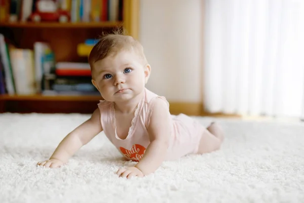 Klein grappig baby meisje tillen lichaam en leren kruipen. — Stockfoto