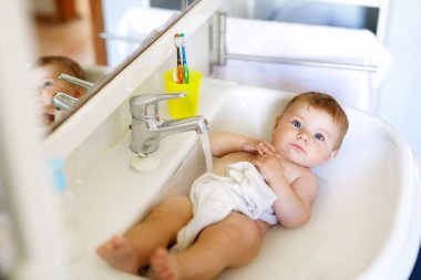 Alarak şirin bebek yıkama lavabo banyo ve musluk suyu yakala.