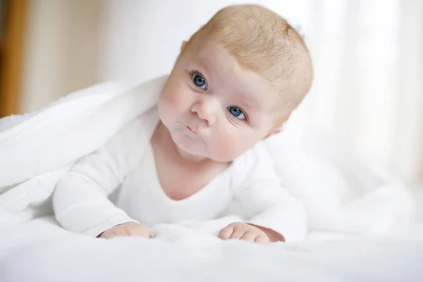 Babymädchen mit weißem Handtuch oder Wintermantel im weißen, sonnigen Schlafzimmer — Stockfoto