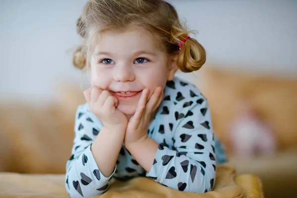 Aranyos kislány hálóinges pizsamában, rajzfilmeket vagy filmet néz a tévében. Boldog egészséges kisbabát otthon. — Stock Fotó