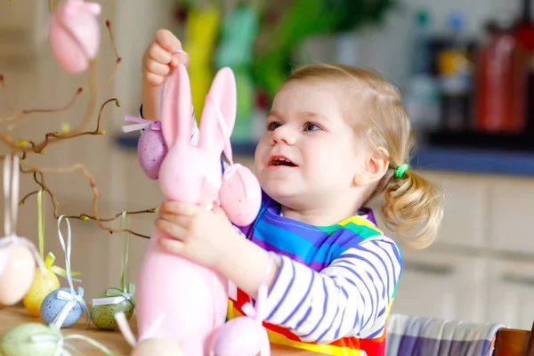 Menina bonito criança decorando árvore e coelho com ovos de plástico pastel coloridos. Criança bebê feliz se divertindo com decorações de Páscoa. Criança sorridente saudável adorável em desfrutar de férias em família — Fotografia de Stock