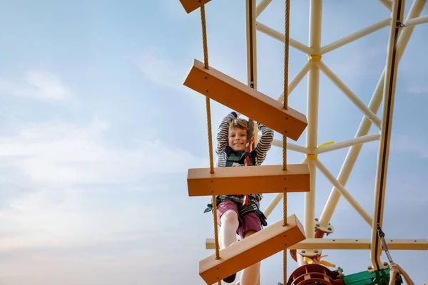 Feliz niño trepando por el sendero de la cuerda alta. Niño activo haciendo aventura y acción en vacaciones familiares. Desafío para niños valientes . —  Fotos de Stock