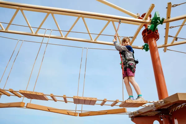 Boldog kisfiú, aki magas kötélpályán mászik. Aktív gyermek, hogy kaland és akció a családi nyaralás. Kihívás a bátor gyerekeknek. — Stock Fotó