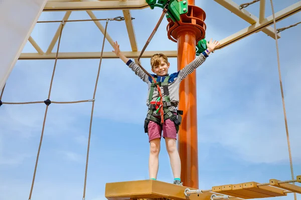 Happy little kid boy climbing on high rope course trail. Active child making adventure and action on family vacations. Challenge for brave kids. — Stock Photo, Image